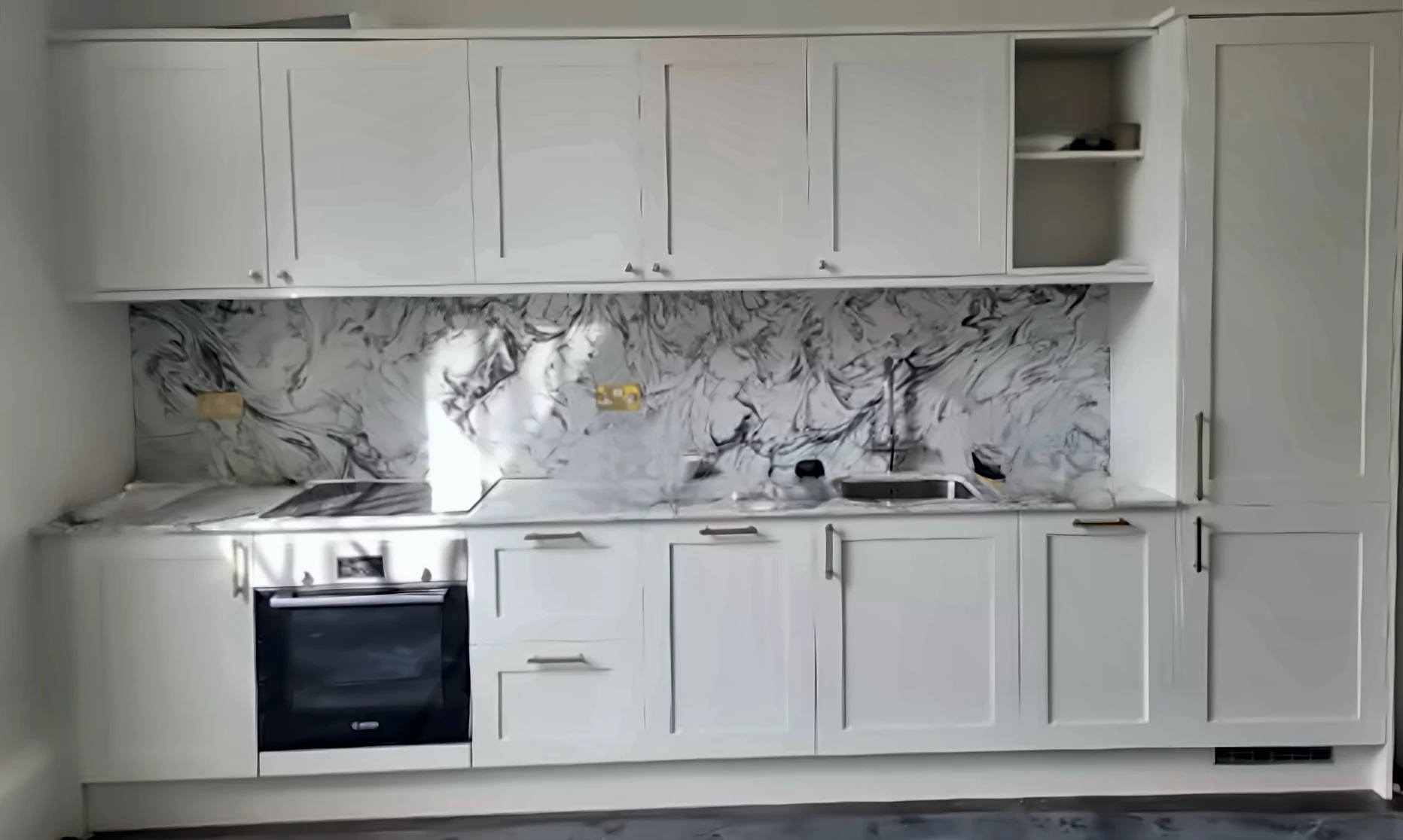 Completed Yadani white Shaker kitchen with brass handles and a marble-effect splashback
