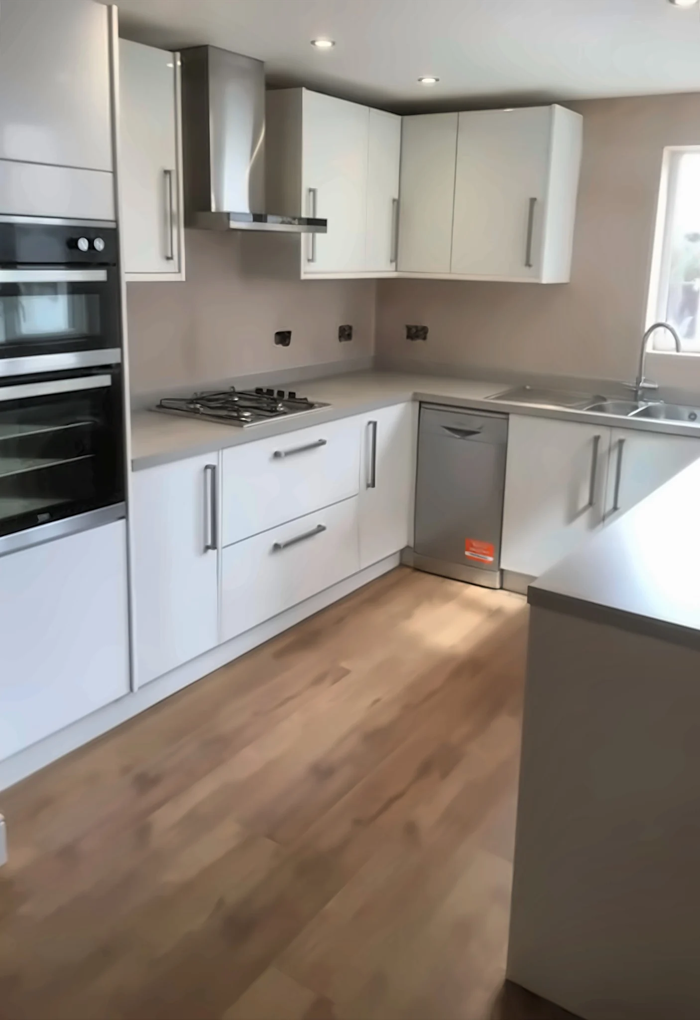 Completed Yadani white gloss fitted kitchen with a double oven tower